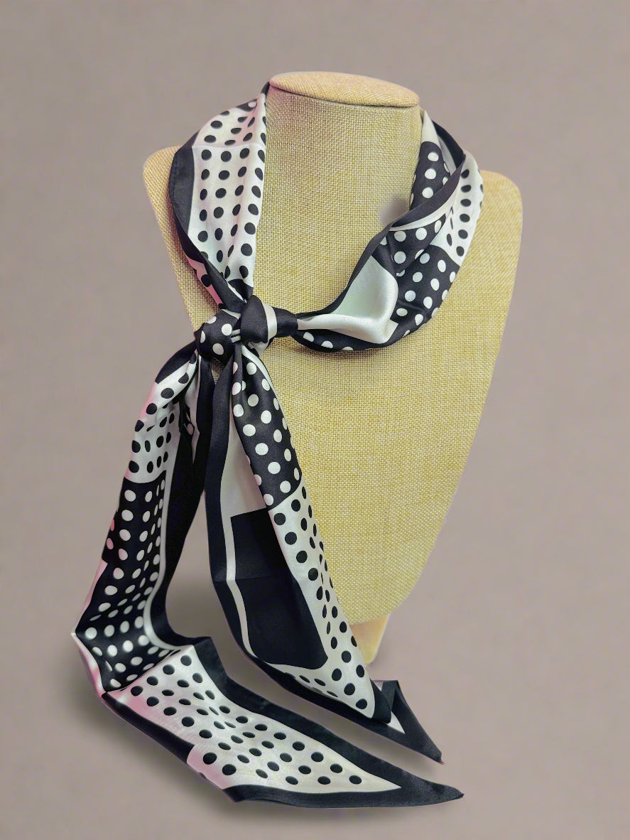 Black and white polka dot scarf on a mannequin head against a pink background