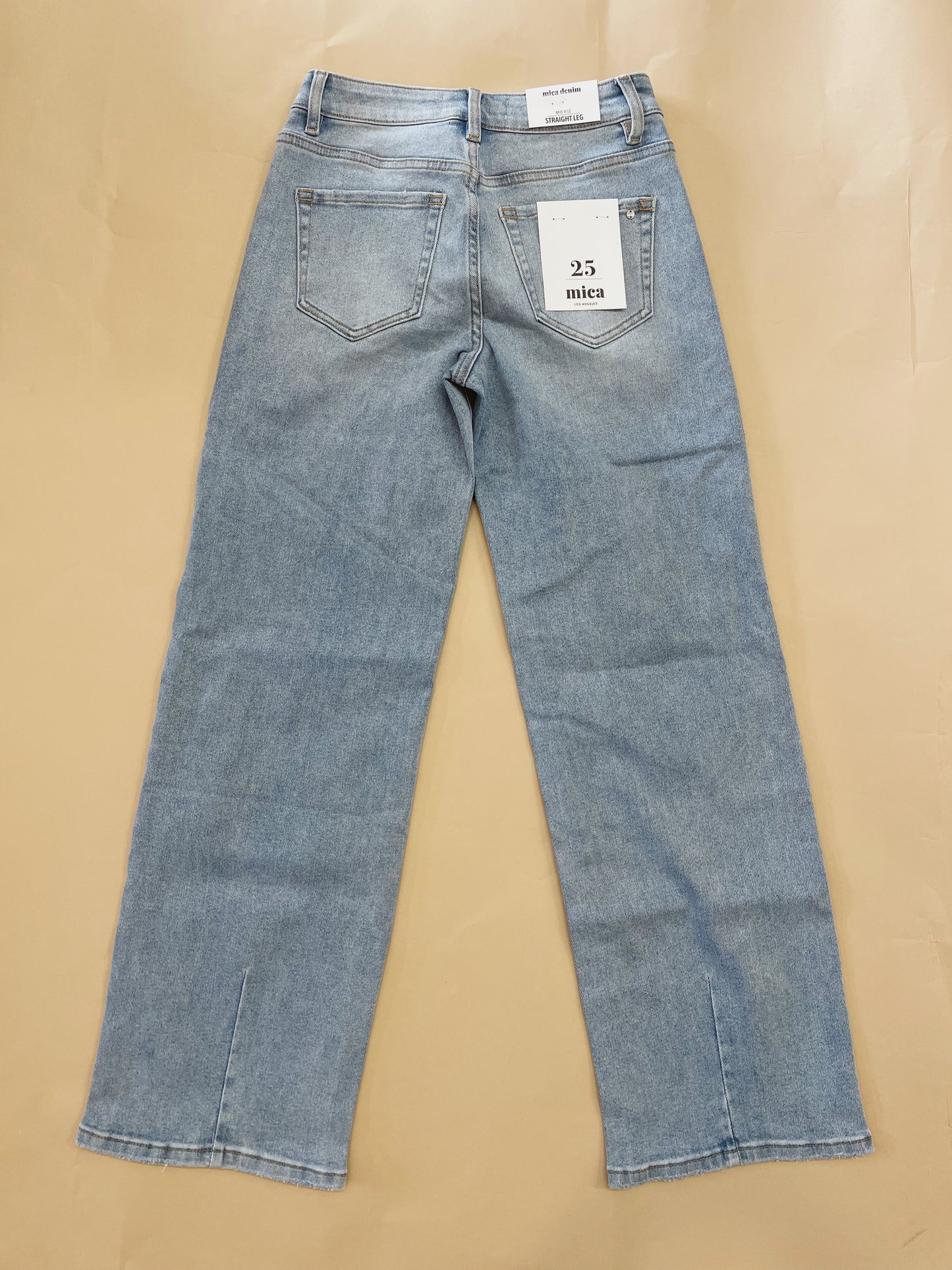Blue jeans with a tag on a beige background
