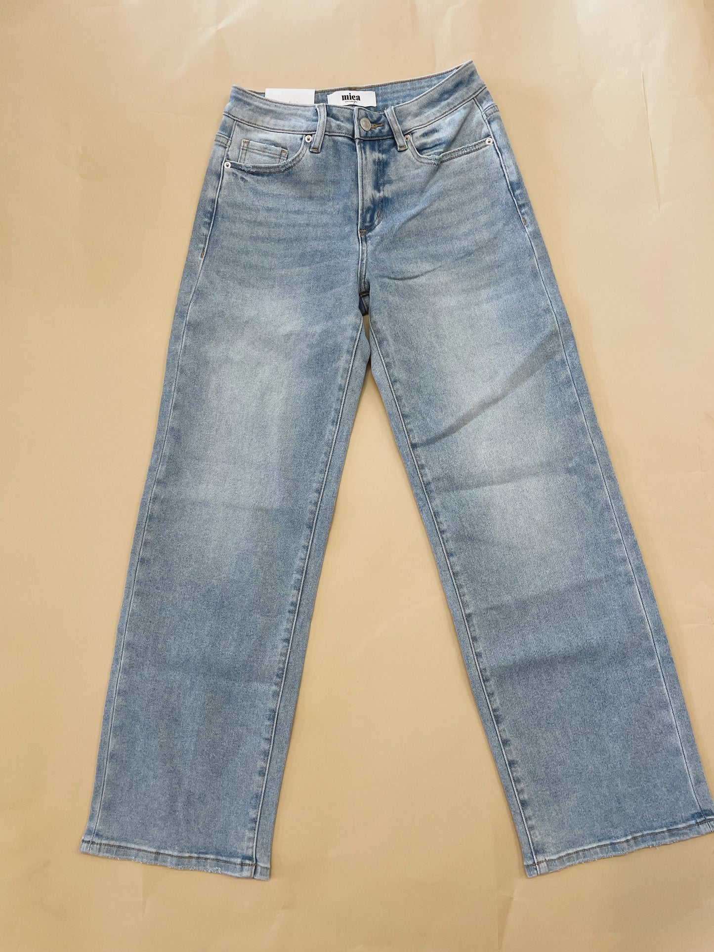 Pair of blue jeans laid flat on a beige surface